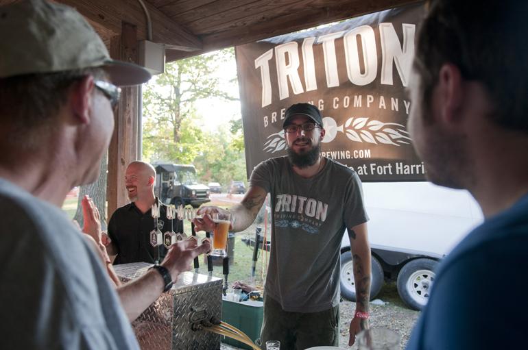 Dain Driscoll serves beer from Triton Brewing Company during the Noblesville Brewfest in Forest Park, Saturday, Sept. 28, 2013.