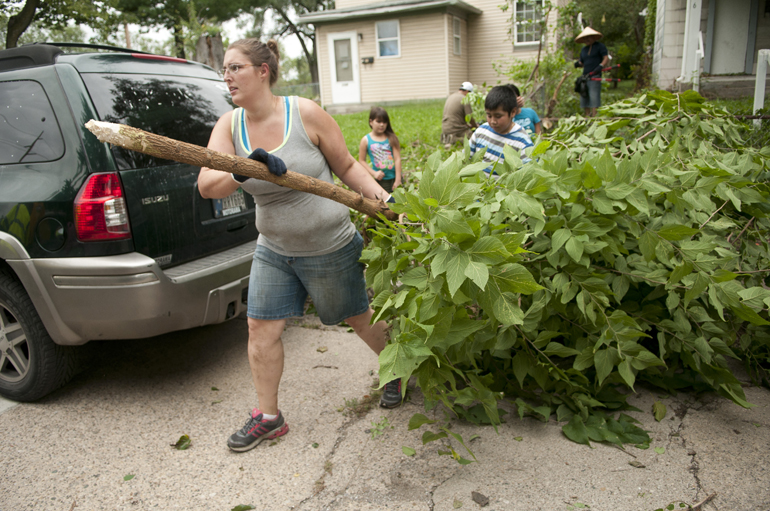 Liz Schrader removes a tree from between two abandoned houses during a community clean-up on South Elder Street near Washington Street, Saturday, Sept. 6, 2014. City organizations lent volunteers and equipment to residents to renovate the high-crime area along West Washington Street.