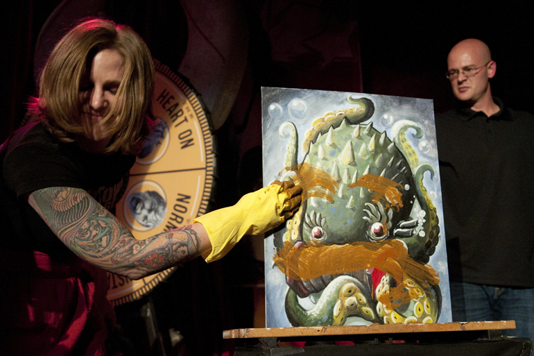 A member of the Naptown Roller Girls cringes as she wipes feces on a painting during the Art vs. Art competition on Friday, Sept. 27, 2013 at The Vogue theatre in Indianapolis. The competition pitted 16 paintings against each other one-on-one, and the piece with less audience support was destroyed by chainsaw, feces, and other means as determined by a Wheel of Death.