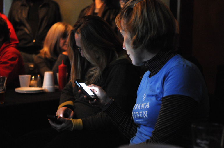 Obama campaign volunteer Caitlin Patterson checks her phone for election returns at a bar near the German Village field office.