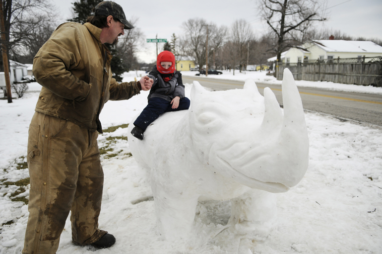 Chip Stoops gives a high-five to his son Hunter as Hunter sits on a rhinoceros snow sculpture Thurs., March 7, 2013, off Poland Hill Road in Lafayette. Stoops said he and Hunter built it together and that Hunter also wanted to make an antelope.