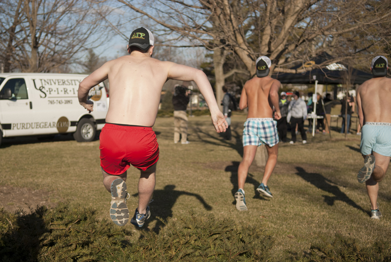 Purdue freshman Trent Nagel jumps over a hedge to follow sophomores Jared Burke and Jacob Baird to register for the Nearly Naked Mile on Thursday, March 21, 2013, on the Purdue campus. The event, run by Purdue Alumni Student Experience, supported Lafayette Transitional Housing.