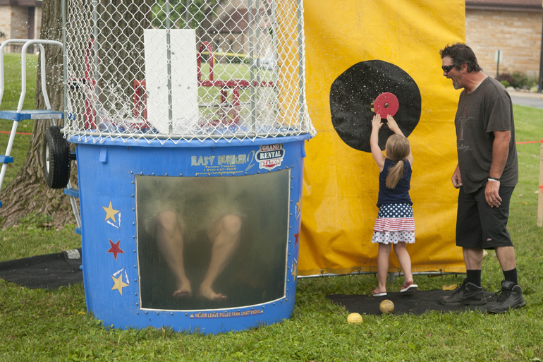 Greenwood Freedom Festival, Saturday, June 28, 2014. Breianna Harlow, 4, with her grandfather Robert McCalister, pushes a button to make Greenwood mayor Mark Myers fall into a dunk tank. The mayor was helping raise money for chemotherapy treatments for two girls at Northeast Elementary School.