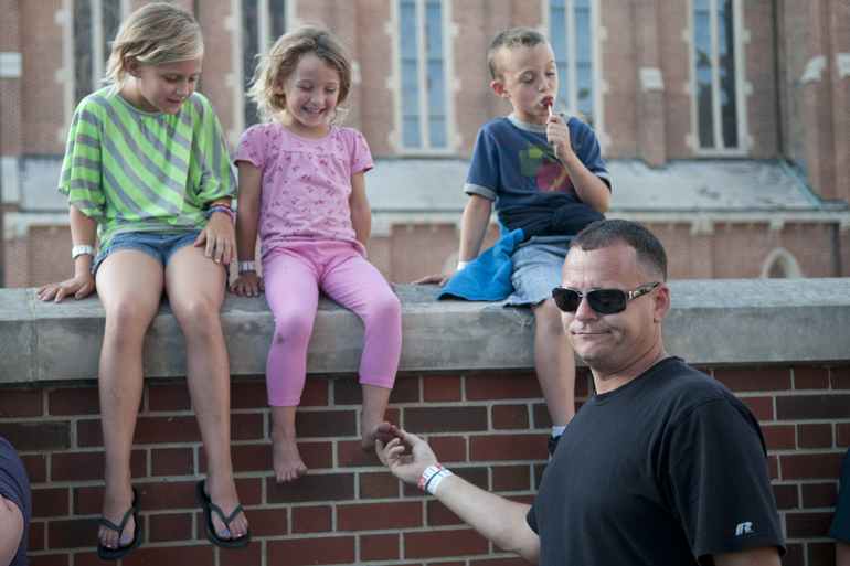 INDYpendence Day Concert on Georgia Street, Friday, July 4, 2014. Lexi, Sammy and DJ Young sit on a brick wall as Eddie DeSaeger tickles Sammy\'s foot.