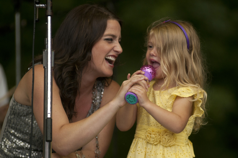 Zanna-Doo vocalist Anne Balbo sings with Molly Szymanski, 3, who begged to go on stage during a Greenwood Summer Concert Series event at the Greenwood Amphitheater, Saturday, July 20, 2013.