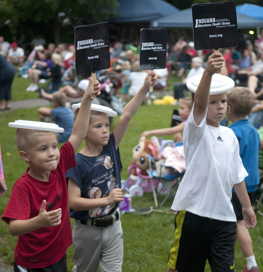 Owen King, 5, Ethan King, 6, and Gavin Armstrong, 7, march with Indiana Members Credit Union signs and Frisbees on their heads during a Greenwood Summer Concert Series event at the Greenwood Amphitheater, Saturday, July 20, 2013.