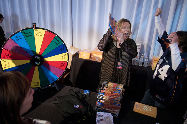 Lauren MacKenzie and Velvet Arrivas of Kroger cheer as they give away packets of bacon earned with a spin of the wheel during Bacon Fest at The Crane Bay, Saturday, Jan. 31, 2015.