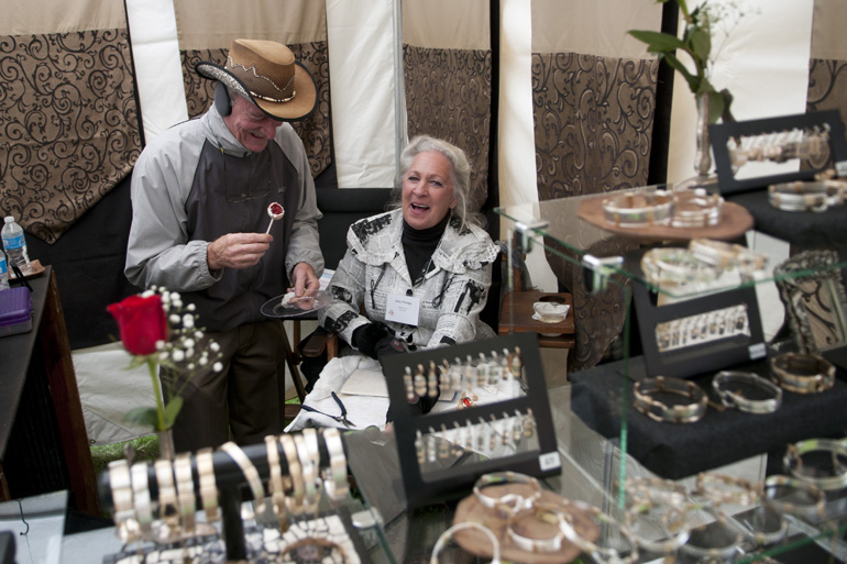 Gilbert Lage and Sally Phillips enjoy a moment behind their art wares during the Indianapolis Art Center\'s preview party for the Broad Ripple Art Fair, Friday, May 16, 2014.