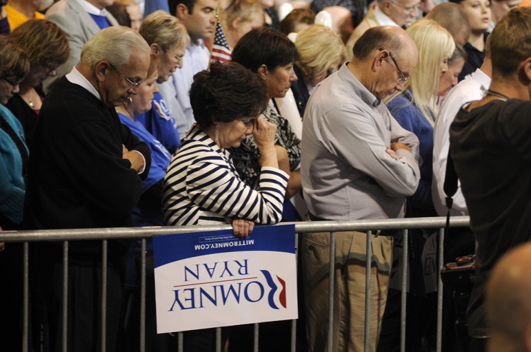 Audience members bow their heads during the invocation before Mitt Romney's presidential campaign stop Sept. 26 in Toledo, Ohio.