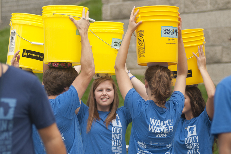 Ashley Cox and her friends carry canal water on their heads during the third annual Walk for Water event downtown, Saturday, Aug. 2, 2014. The event raised money for a community clean-water well in Kager, Kenya. Attendees walked from American Legion Mall to the canal, filled buckets with water and walked back to the mall, simulating the path villagers without clean water have to take every day.