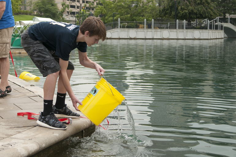 Aaron Coats, 13, retrieves water from the canal during the third annual Walk for Water event downtown, Saturday, Aug. 2, 2014. The event raised money for a community clean-water well in Kager, Kenya. Attendees walked from American Legion Mall to the canal, filled buckets with water and walked back to the mall, simulating the path villagers without clean water have to take every day.