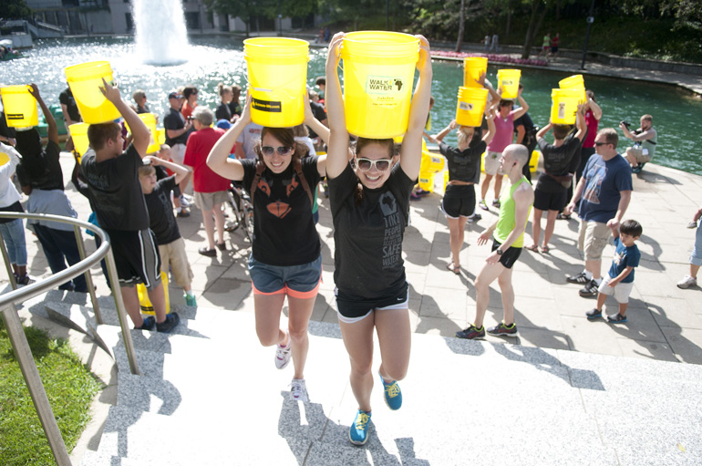 Molly Martin and Grace Connell lead others with water buckets up the steps of the White River Canal during the Walk for Water 5K event, Saturday, July 27, 2013.