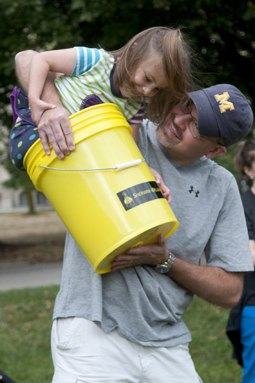 Reagan Wolfe, 5, is lifted by her father, Chad, in a bucket that will be filled with water during the Walk for Water 5K event at American Legion Mall, Saturday, July 27, 2013.