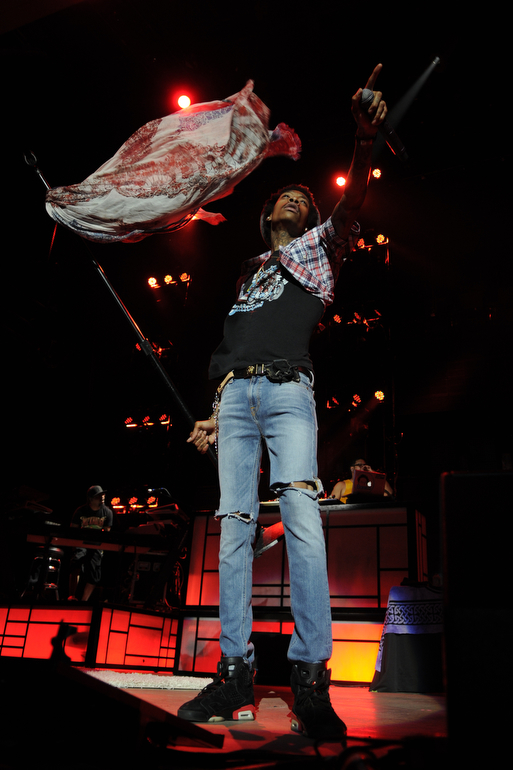 Wiz Khalifa points to the crowd as lifts the microphone stand during his concert with Mac Miller and Kendrick Lamar on Jul. 28, 2012, at Klipsch Music Center near Indianapolis.